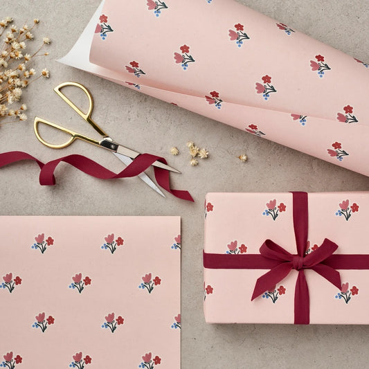 Katie Leamon Wallpaper Posy pink gift wrap with scattered floral motif, shown rolled, flat and wrapped around a gift with dark red ribbon